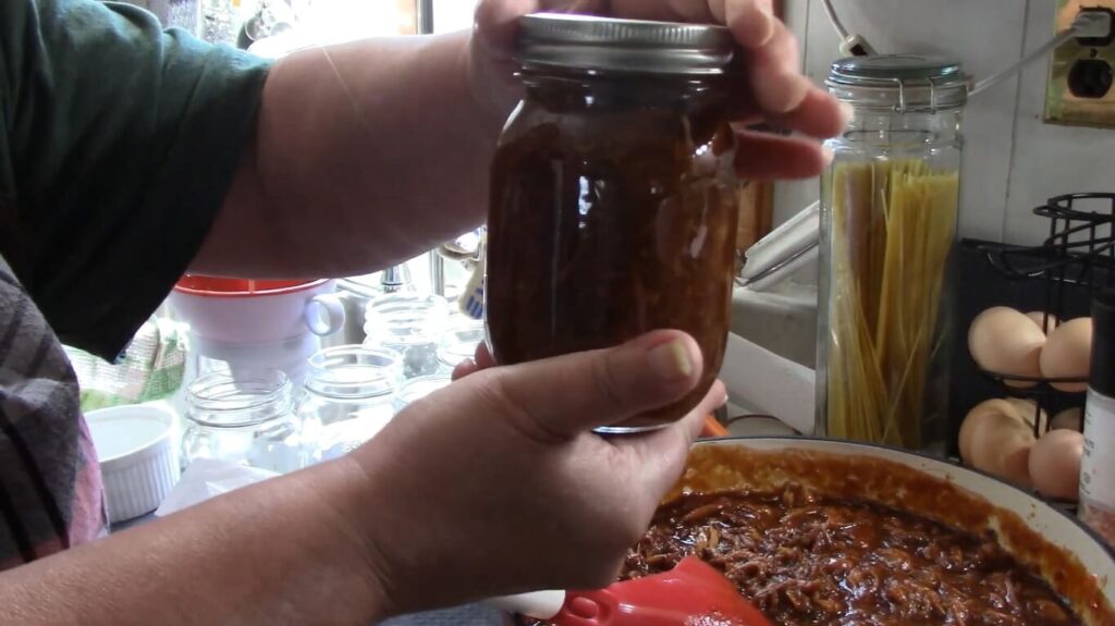 Next, load the processed, shredded pulled pork mixture and BBQ sauce into each jar, preparing for pressure canning