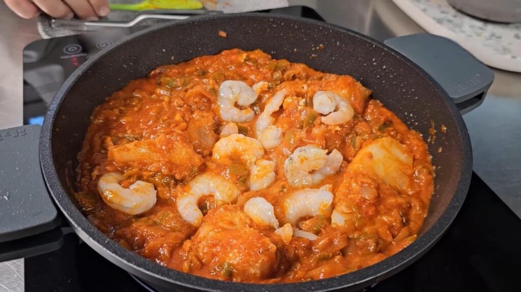 And finally, bring in the taste of the sea with fresh prawn pieces, let them harmonize with Bacalao Ajoarriero, and bring it all to a boil.